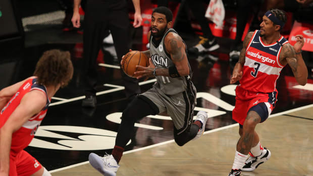 Brooklyn Nets point guard Kyrie Irving (11) drives to the basket against Washington Wizards center Robin Lopez (15) and shooting guard Bradley Beal (3) during the second quarter at Barclays Center.